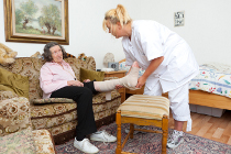 Pfleger gießt Seniorin ein Glas Wasser ein